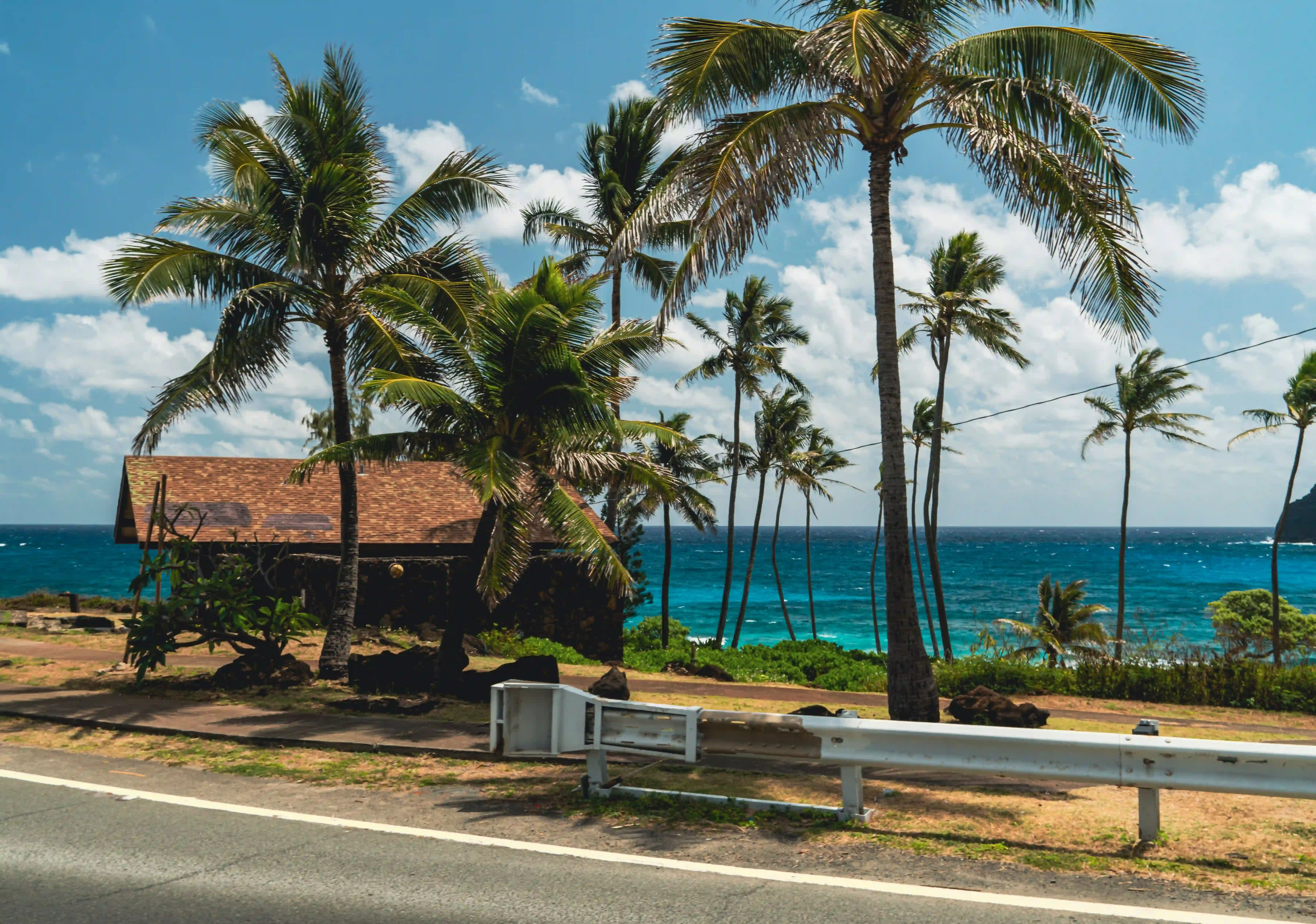 A hale beside the highway above a turquoise bay